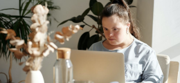 A woman with Down Syndrome, working on a laptop in a modern apartment
